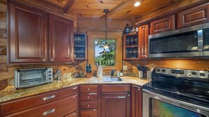 Une cuisine avec des meubles de rangement en bois, un four à micro-ondes encastré, une cuisinière et un grille-pain.