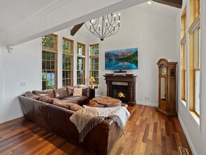 A living room with a sectional sofa, a fireplace, a television, and large windows. - Arrant Ridge - Long Range Mountain Views | Pet Friendly | Hot Tub | Firepit | Game Room (Blairsville)