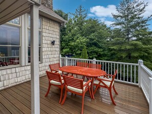 A wooden deck with a round table and chairs, a stone chimney, and a white railing. - Arrant Ridge - Long Range Mountain Views | Pet Friendly | Hot Tub | Firepit | Game Room (Blairsville)