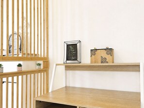 A room with a wooden slatted partition, a framed picture on a shelf, and a small cabinet with decorative patterns. - Les Glaieuls by Interhome (Deauville-Trouville)