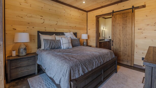 A bedroom with a wooden ceiling, a bed with grey bedding, two bedside tables with lamps, and a wooden wardrobe. - Pickleball Court, Heated Pool, Mtn Views, luxury finishes, close to town (Blue Ridge)