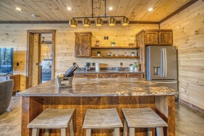 A wooden interior with a central island, bar stools, a refrigerator, and pendant lighting. - Pickleball Court, Heated Pool, Mtn Views, luxury finishes, close to town (Blue Ridge)