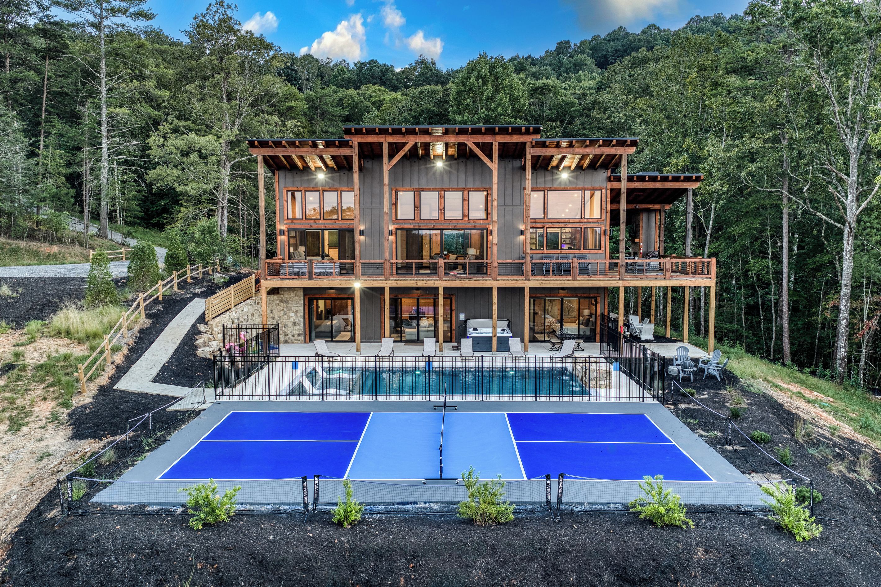 A two-story wooden cabin with a pool and tennis courts.