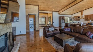 A spacious living area with a fireplace, leather sofas, and a kitchen in the background. - Pickleball Court, Heated Pool, Mtn Views, luxury finishes, close to town (Blue Ridge)