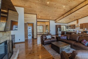A spacious living area with a fireplace, leather sofas, and a kitchen in the background. - Pickleball Court, Heated Pool, Mtn Views, luxury finishes, close to town (Blue Ridge)