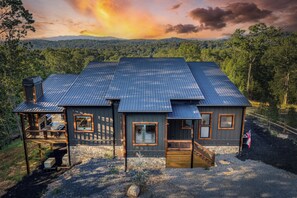A two-story house with a metal roof, wooden deck, and a stone foundation. - Pickleball Court, Heated Pool, Mtn Views, luxury finishes, close to town (Blue Ridge)