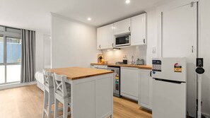 A modern kitchen with white cabinetry, a wooden countertop, and a built-in microwave. - Newland Heights Rooftop Pool & Bondi Living (Bondi Junction)