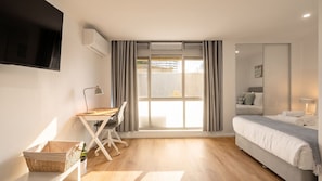 A modern bedroom with a bed, desk, chair, and a TV mounted on the wall. - Newland Heights Rooftop Pool & Bondi Living (Bondi Junction)