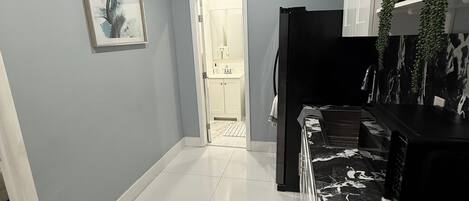 A modern kitchen with a black refrigerator, white cabinets, and a tiled floor.