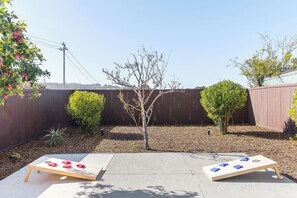 Ein Garten mit Holzzaun, zwei Bäumen und zwei Shuffleboard-Platten.