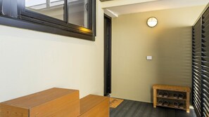 A room with a wooden bench, a shoe rack, and a door leading to another space. - The Plot Twist Randwick Unit 2 (Randwick)