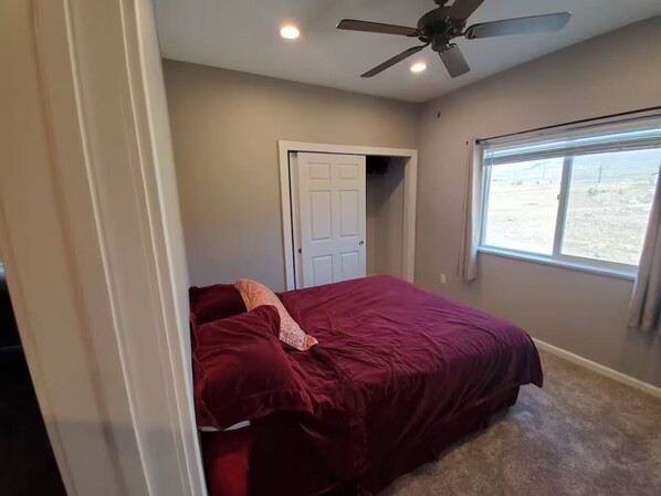 A bedroom with a bed, a ceiling fan, a window, and a door. - CO Mountain getaway (Kremmling)