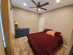 Ein Schlafzimmer mit einem Bett, einem Schminktisch, einem Deckenventilator und einer Tür.