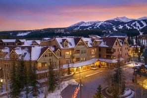 A large, multi-story hotel with a symmetrical facade, snow-covered roofs, and a mountain backdrop. - Hyatt Main St Studio | Steps to Peak 9 + Downtown (Breckenridge)