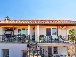 A two-story building with a tiled roof, a balcony with outdoor furniture, and a staircase leading to the upper floor. - MLIKOTA / HR-07266-01 by Interhome (Crikvenica/Dramalj)