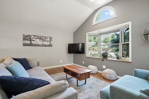 A living room with a grey wall, a large window, a flat-screen TV, a wooden coffee table, a grey sofa, and a blue armchair. - Spacious Golden Home Near Red Rocks & DT with EV (Golden)