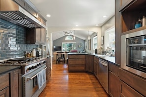 A modern kitchen with a central island, stainless steel appliances, and a wooden floor. - Spacious Golden Home Near Red Rocks & DT with EV (Golden)