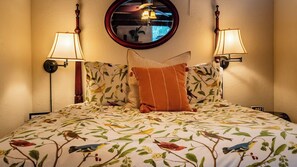 A hotel room with a bed featuring a floral print bedspread, two wall-mounted lamps, and a round mirror above the bed. - Room With A View by Avantstay King Studio + Loft + Full Kitchen Oak Hills + 30 Min to Coast (Paso Robles)