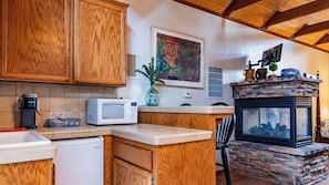 A kitchen with wooden cabinets, a microwave, a coffee maker, and a stone fireplace. - Room With A View by Avantstay King Studio + Loft + Full Kitchen Oak Hills + 30 Min to Coast (Paso Robles)