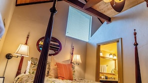 A bedroom with a four-poster bed, two wall-mounted lamps, a round mirror, and a bathroom visible through an open door. - Room With A View by Avantstay King Studio + Loft + Full Kitchen Oak Hills + 30 Min to Coast (Paso Robles)