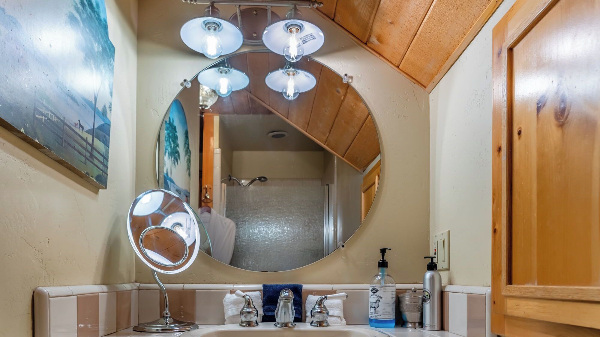 A bathroom with a round mirror, a sink, and a shower.