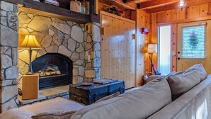 Una habitación acogedora con chimenea de piedra, un sofá y una ventana con persianas.