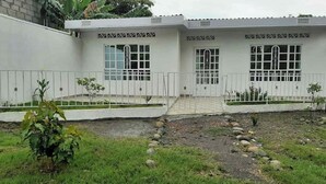 Ein Gebäude mit weißer Fassade, mehreren Fenstern und einem begrenzten Eingangsbereich.