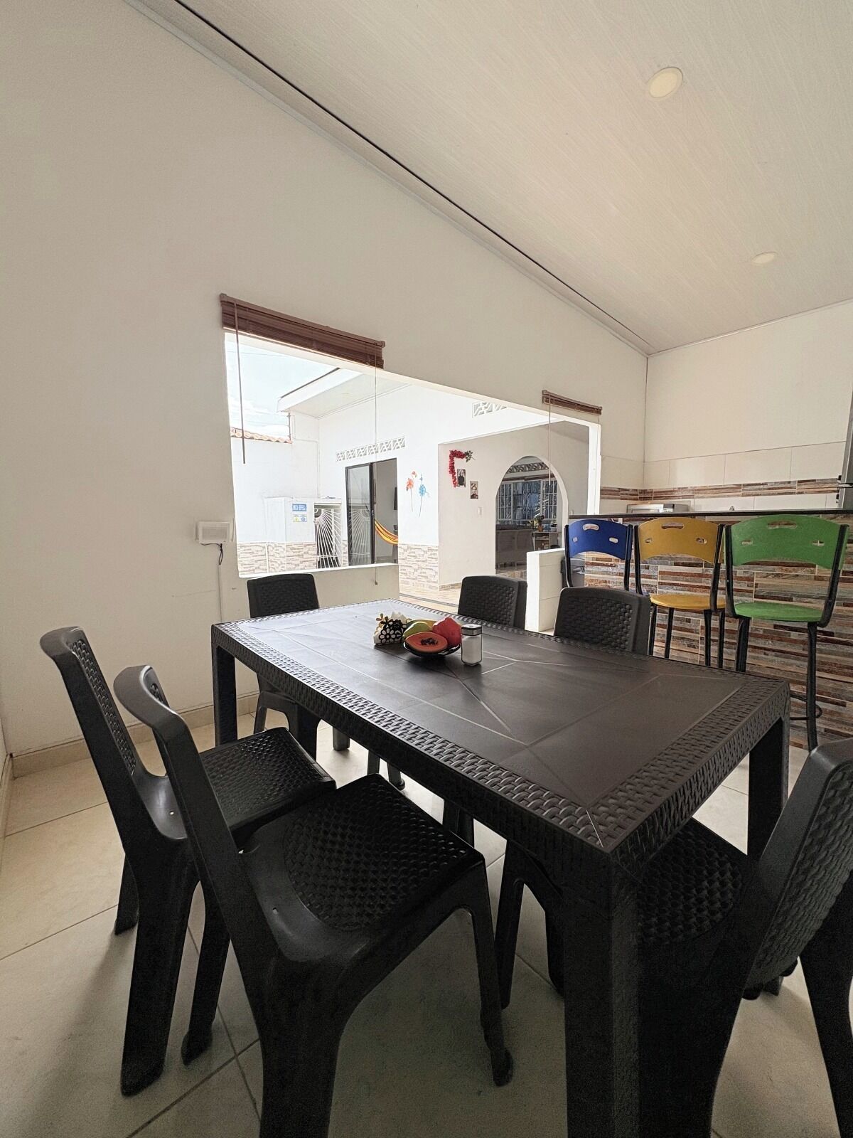 Comedor con mesa y sillas, vistas al exterior y zona de cocina con sillas.