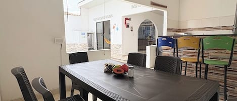Comedor con mesa y sillas, vistas al exterior y zona de cocina con sillas.