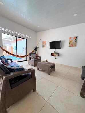 A spacious living area with a large window, a flat-screen TV, and a hammock.