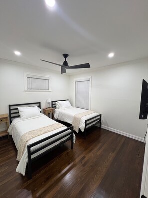 A bedroom with two beds, a ceiling fan, and a TV mounted on the wall. - Renovated 2BR in Irving - King Bed (Irving)