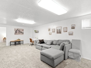 A spacious living room with a sectional sofa, a small table, and a chair. - Pet-Friendly 4BR - Free Parking - Utah Retreat (West Valley City)