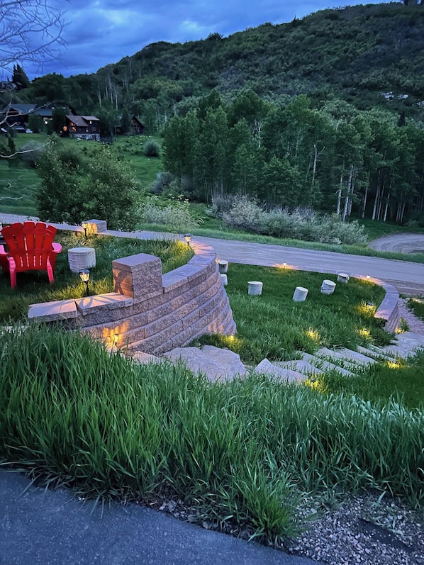 A landscaped garden with a red chair, stone steps, and a pathway leading to a house.
