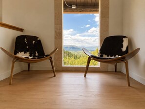 Two chairs with a view of a landscape through a window.