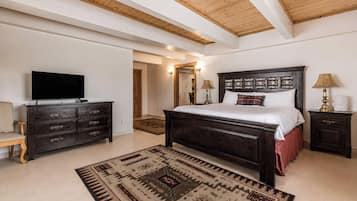 Un dormitorio con una cama grande, televisor, cómoda y alfombra.