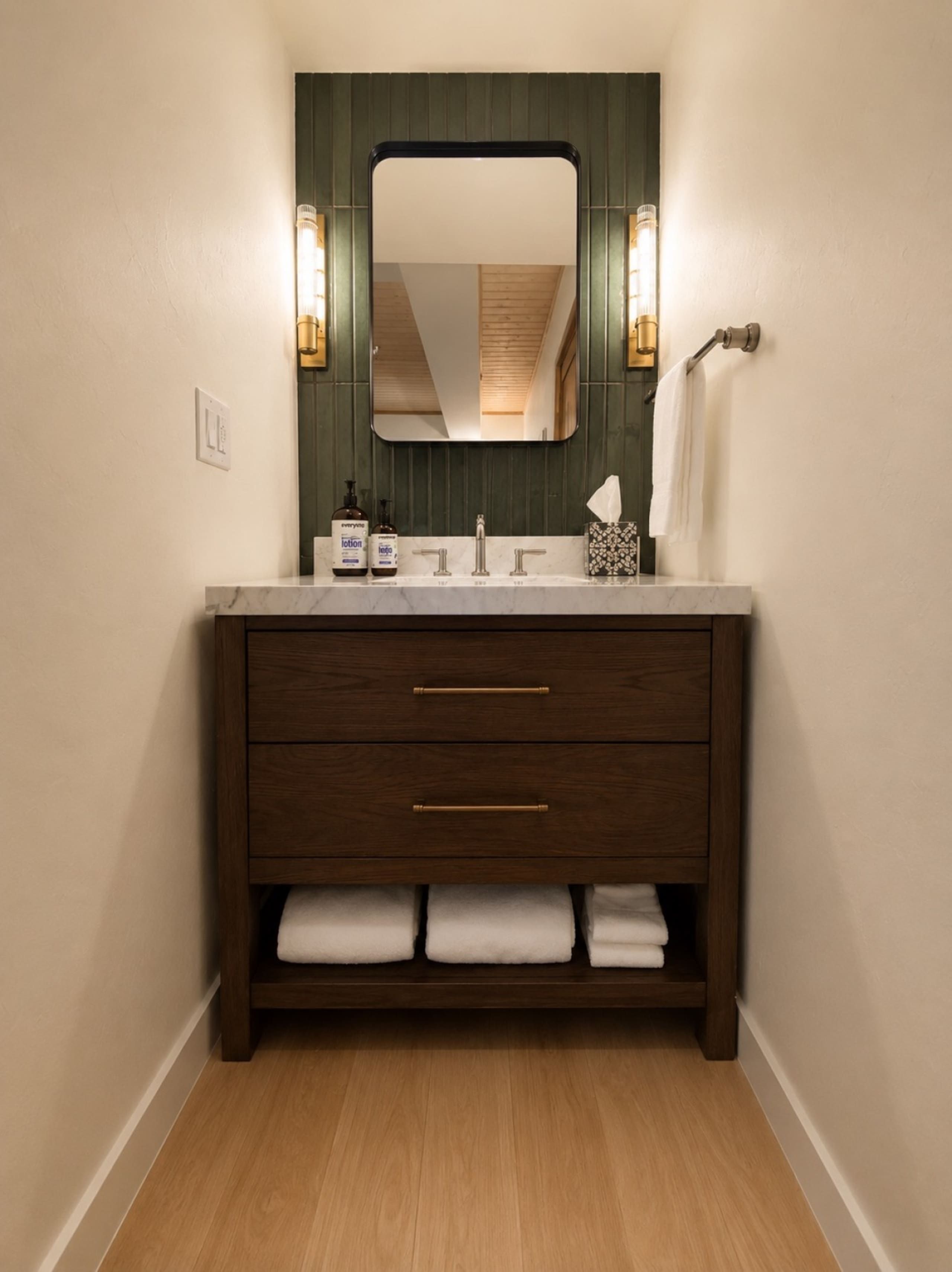 Un baño con tocador de madera, un espejo y dos luces fijadas a la pared.
