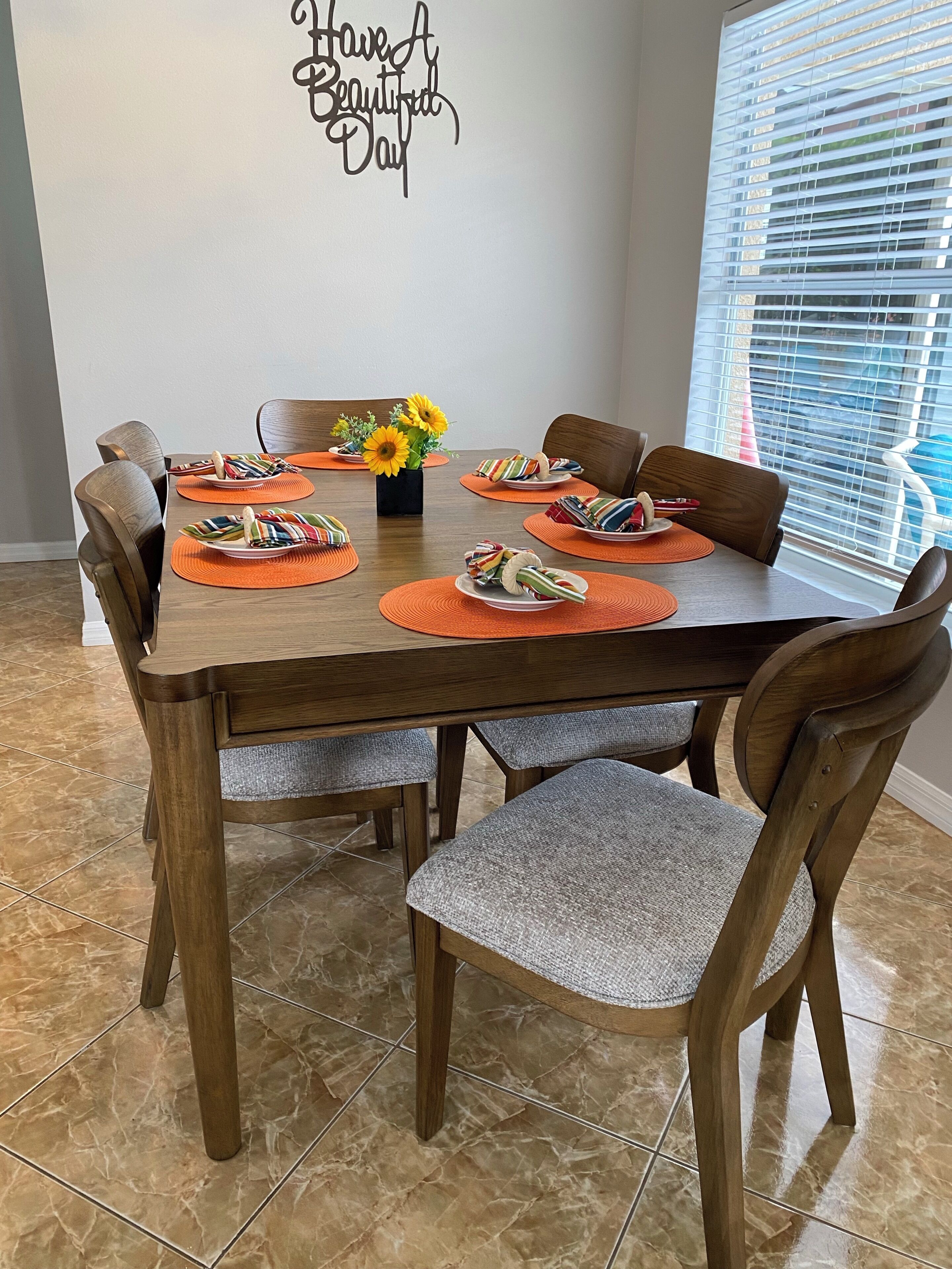 A dining area with a wooden table, chairs, and a wall sign.