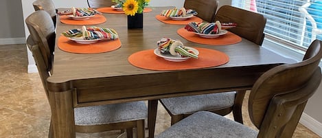 A dining area with a wooden table, chairs, and a wall sign.