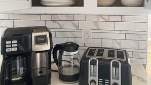 A kitchen with a coffee maker, toaster, and a cabinet with colorful dishes and plates. - Charming residence with a private pool located in proximity to Disney World (Kissimmee)