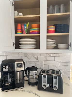 A kitchen with a coffee maker, toaster, and a cabinet with colorful dishes and plates. - Charming residence with a private pool located in proximity to Disney World (Kissimmee)