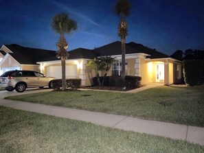 A residential house with a driveway, a parked car, and two palm trees. - Charming residence with a private pool located in proximity to Disney World (Kissimmee)