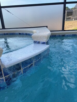 A pool with a built-in seating area and a clear view of the surrounding landscape. - Charming residence with a private pool located in proximity to Disney World (Kissimmee)
