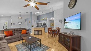 A modern living room with a sofa, coffee table, and dining area. - Charming residence with a private pool located in proximity to Disney World (Kissimmee)