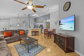 A modern living room with a sofa, coffee table, and dining area. - Charming residence with a private pool located in proximity to Disney World (Kissimmee)