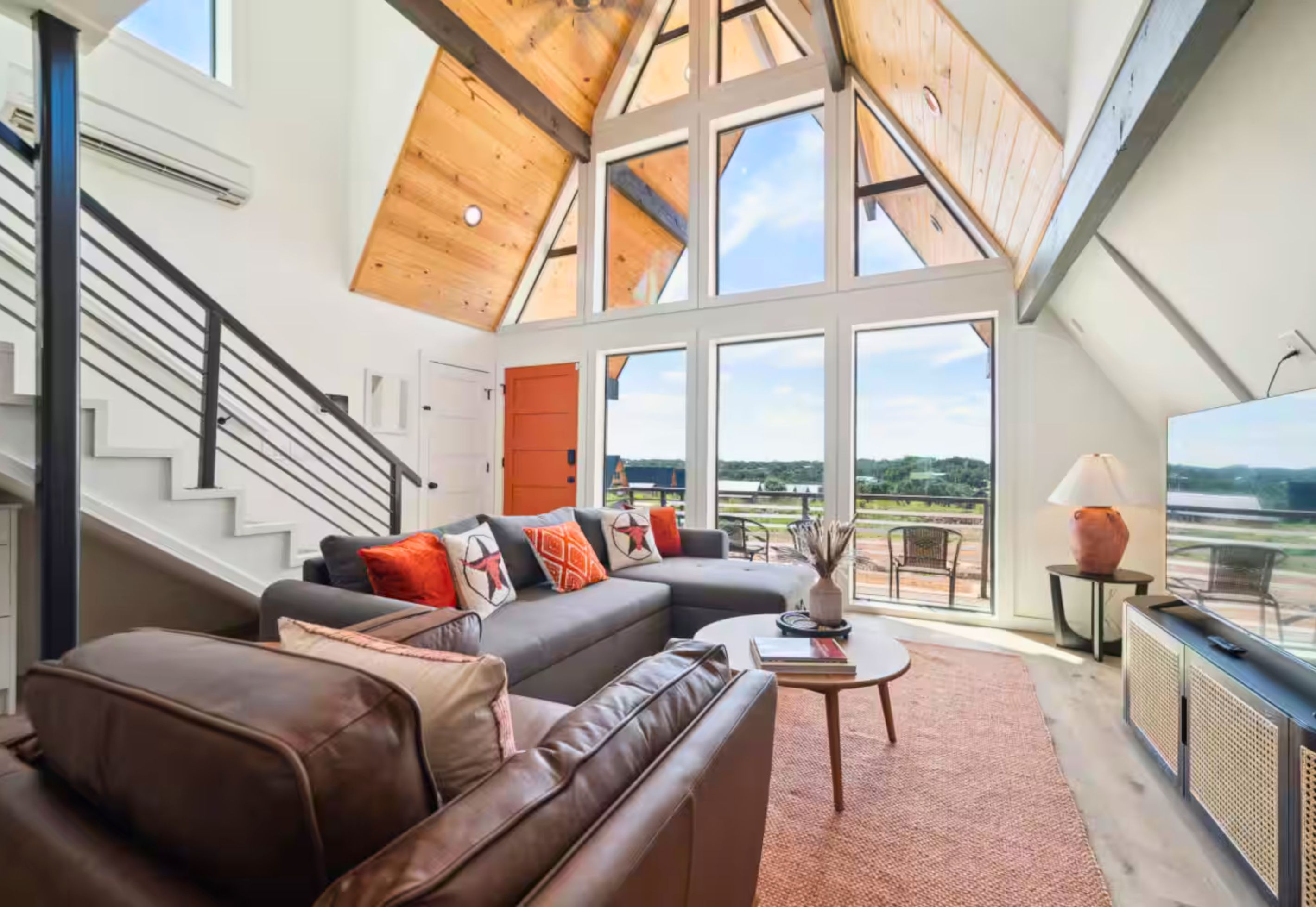 A spacious living area with a high ceiling, a leather sofa, a coffee table, and a view of the outdoors.