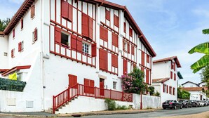Un immeuble de deux étages avec une façade blanche et des encadrements de fenêtres rouges.