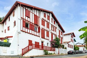 A two-story building with a white facade and red window frames. - Studio Baignol - Welkeys (Ciboure)