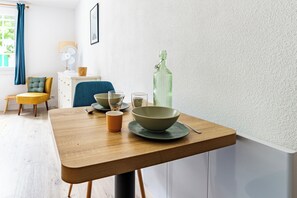 A dining area with a wooden table, bowls, a glass, and a bottle. - Studio Baignol - Welkeys (Ciboure)