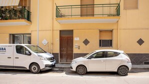 A white van and a white car parked in front of a building with a balcony and a door. - The Ancient Sailing Ship - Alghero (Alghero)
