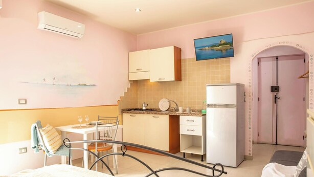 A compact kitchen with a dining area, a refrigerator, and a television mounted on the wall. - The Ancient Sailing Ship - Alghero (Alghero)